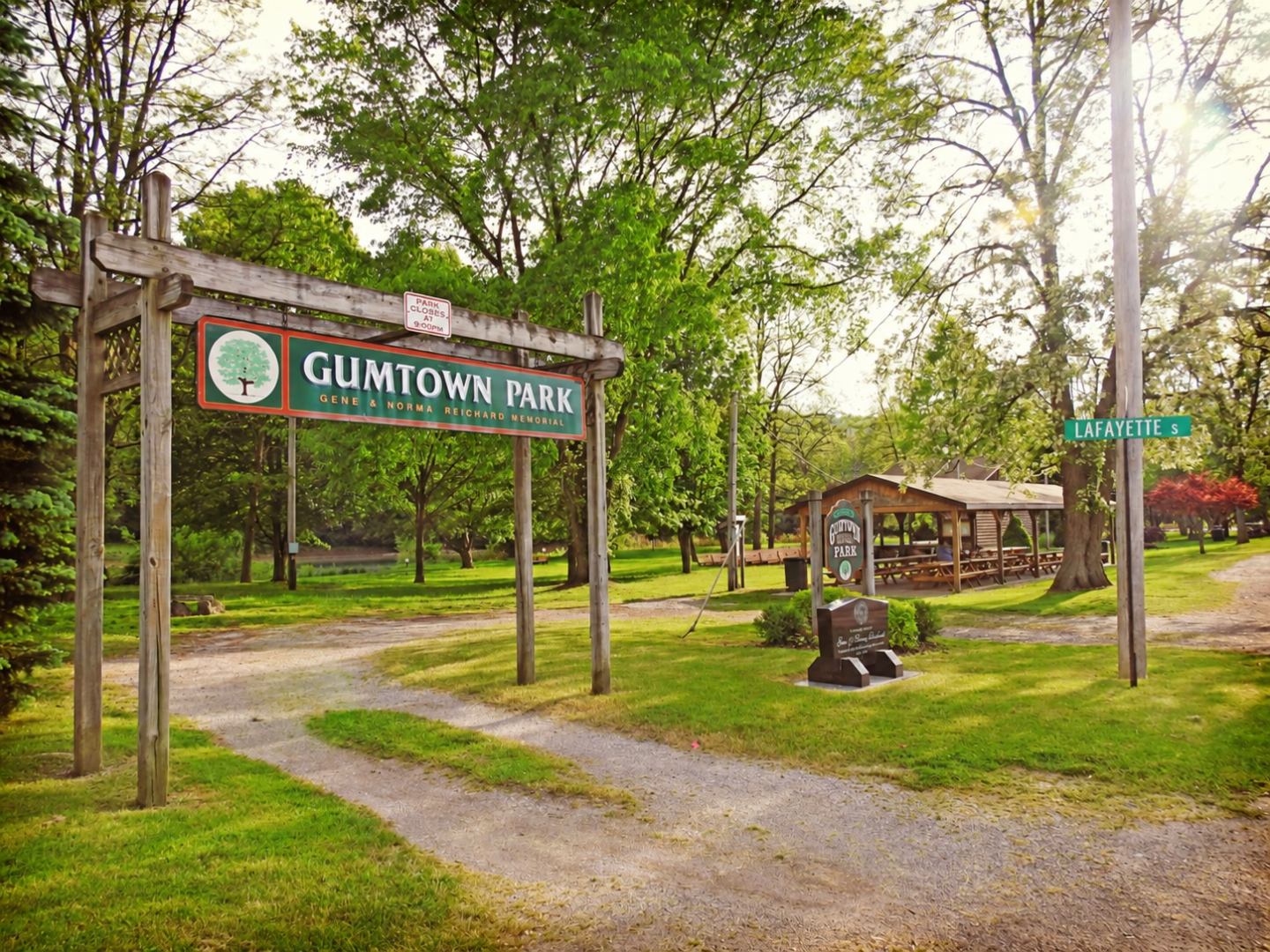 Gumtown Park entrance sign, memorial and picnic pavilion surrounded by trees